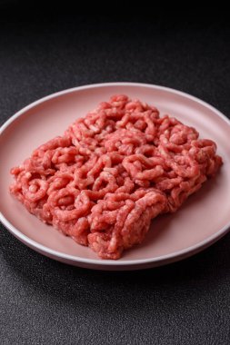 Siyah bir zemin üzerinde tuz ve baharatla doldurulmuş çiğ et ya da domuz eti.