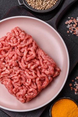 Siyah bir zemin üzerinde tuz ve baharatla doldurulmuş çiğ et ya da domuz eti.