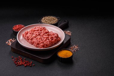 Siyah bir zemin üzerinde tuz ve baharatla doldurulmuş çiğ et ya da domuz eti.