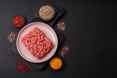 Siyah bir zemin üzerinde tuz ve baharatla doldurulmuş çiğ et ya da domuz eti.