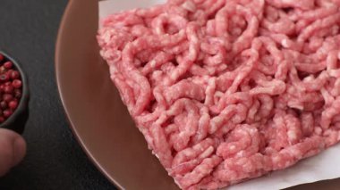 Siyah bir zemin üzerinde tuz ve baharatla doldurulmuş çiğ et ya da domuz eti.