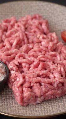 Siyah bir zemin üzerinde tuz ve baharatla doldurulmuş çiğ et ya da domuz eti.