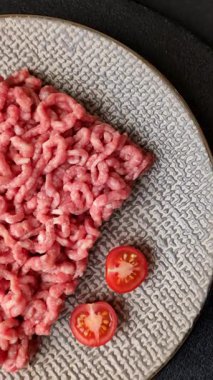 Siyah bir zemin üzerinde tuz ve baharatla doldurulmuş çiğ et ya da domuz eti.