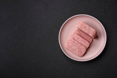 Konserve jambon, et, domuz eti, baharat ve tuzlu, koyu beton arka planda dilimler.