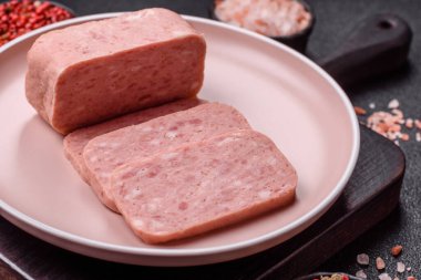 Konserve jambon, et, domuz eti, baharat ve tuzlu, koyu beton arka planda dilimler.