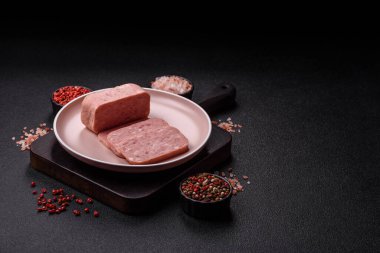 Konserve jambon, et, domuz eti, baharat ve tuzlu, koyu beton arka planda dilimler.