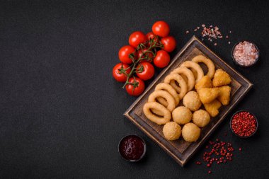 Yiyecek, tavuk nugget, soğan halkaları ve arka planda peynir topları. Fast food, sağlıksız yaşam tarzı