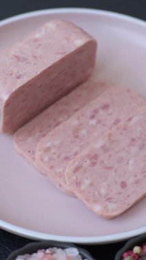 Konserve jambon, et, domuz eti, baharat ve tuzlu, koyu beton arka planda dilimler.