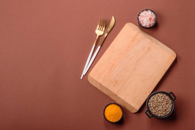Tek renkli kahverengi arka planda boş ahşap kesim tahtası. Yemek masasında çatal bıçak takımı olan boş bir tahta.