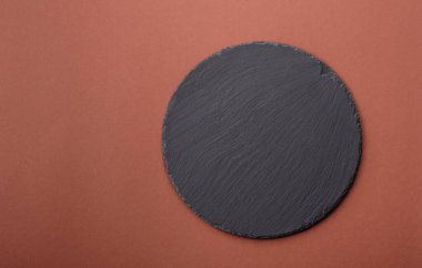 Tek renkli kahverengi arka planda boş seramik plaka. Yemek masasında çatal bıçak takımı olan boş bir tabak.