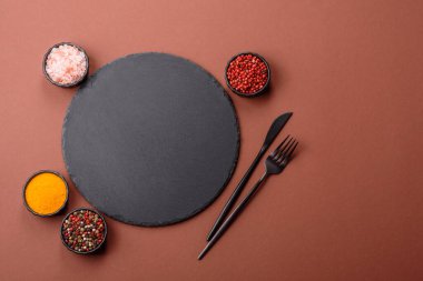 Tek renkli kahverengi arka planda boş seramik plaka. Yemek masasında çatal bıçak takımı olan boş bir tabak.