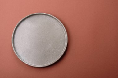 Tek renkli kahverengi arka planda boş seramik plaka. Yemek masasında çatal bıçak takımı olan boş bir tabak.