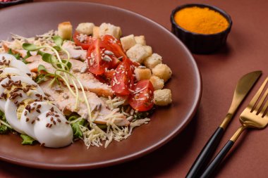 İçinde tavuk, parmesan peyniri, domates, kızarmış ekmek, marul yaprağı, keten tohumu, ayçiçeği ve susam tohumları olan bir kâse dolusu sezar salatası.