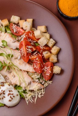 İçinde tavuk, parmesan peyniri, domates, kızarmış ekmek, marul yaprağı, keten tohumu, ayçiçeği ve susam tohumları olan bir kâse dolusu sezar salatası.