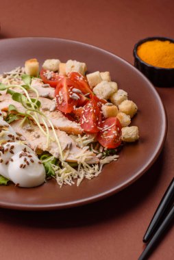 İçinde tavuk, parmesan peyniri, domates, kızarmış ekmek, marul yaprağı, keten tohumu, ayçiçeği ve susam tohumları olan bir kâse dolusu sezar salatası.