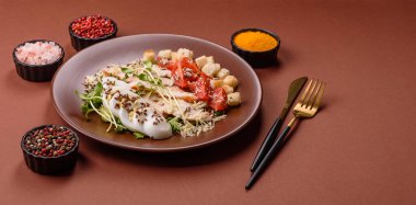 İçinde tavuk, parmesan peyniri, domates, kızarmış ekmek, marul yaprağı, keten tohumu, ayçiçeği ve susam tohumları olan bir kâse dolusu sezar salatası.