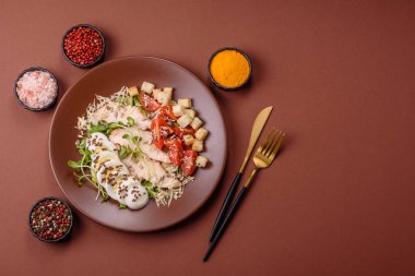 İçinde tavuk, parmesan peyniri, domates, kızarmış ekmek, marul yaprağı, keten tohumu, ayçiçeği ve susam tohumları olan bir kâse dolusu sezar salatası.