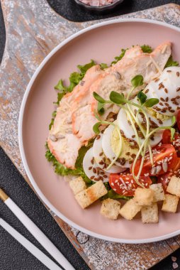 İçinde tavuk, parmesan peyniri, domates, kızarmış ekmek, marul yaprağı, keten tohumu, ayçiçeği ve susam tohumları olan bir kâse dolusu sezar salatası.