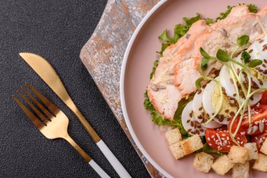 İçinde tavuk, parmesan peyniri, domates, kızarmış ekmek, marul yaprağı, keten tohumu, ayçiçeği ve susam tohumları olan bir kâse dolusu sezar salatası.