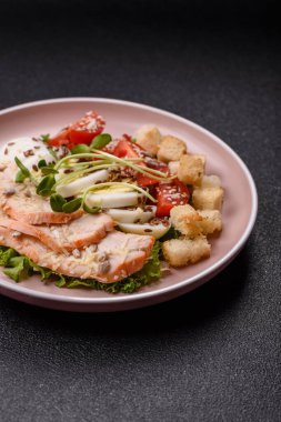 İçinde tavuk, parmesan peyniri, domates, kızarmış ekmek, marul yaprağı, keten tohumu, ayçiçeği ve susam tohumları olan bir kâse dolusu sezar salatası.