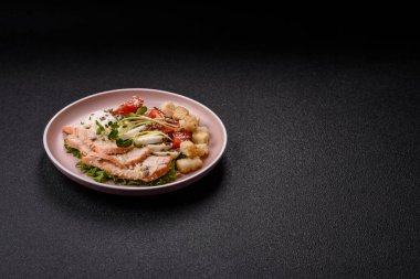 İçinde tavuk, parmesan peyniri, domates, kızarmış ekmek, marul yaprağı, keten tohumu, ayçiçeği ve susam tohumları olan bir kâse dolusu sezar salatası.