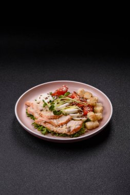 İçinde tavuk, parmesan peyniri, domates, kızarmış ekmek, marul yaprağı, keten tohumu, ayçiçeği ve susam tohumları olan bir kâse dolusu sezar salatası.