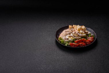 İçinde tavuk, parmesan peyniri, domates, kızarmış ekmek, marul yaprağı, keten tohumu, ayçiçeği ve susam tohumları olan bir kâse dolusu sezar salatası.