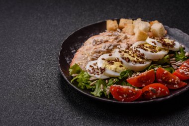 İçinde tavuk, parmesan peyniri, domates, kızarmış ekmek, marul yaprağı, keten tohumu, ayçiçeği ve susam tohumları olan bir kâse dolusu sezar salatası.