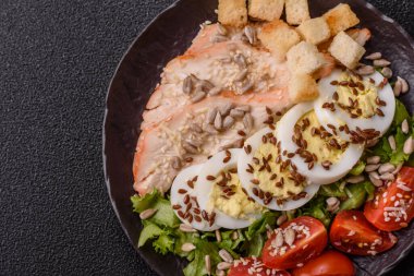 İçinde tavuk, parmesan peyniri, domates, kızarmış ekmek, marul yaprağı, keten tohumu, ayçiçeği ve susam tohumları olan bir kâse dolusu sezar salatası.