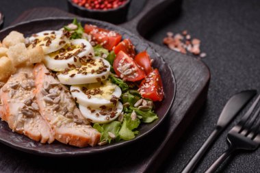 İçinde tavuk, parmesan peyniri, domates, kızarmış ekmek, marul yaprağı, keten tohumu, ayçiçeği ve susam tohumları olan bir kâse dolusu sezar salatası.