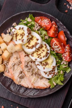 İçinde tavuk, parmesan peyniri, domates, kızarmış ekmek, marul yaprağı, keten tohumu, ayçiçeği ve susam tohumları olan bir kâse dolusu sezar salatası.