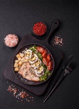 İçinde tavuk, parmesan peyniri, domates, kızarmış ekmek, marul yaprağı, keten tohumu, ayçiçeği ve susam tohumları olan bir kâse dolusu sezar salatası.