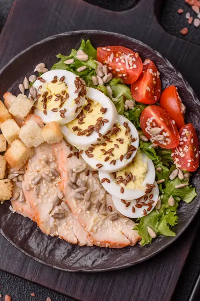 İçinde tavuk, parmesan peyniri, domates, kızarmış ekmek, marul yaprağı, keten tohumu, ayçiçeği ve susam tohumları olan bir kâse dolusu sezar salatası.