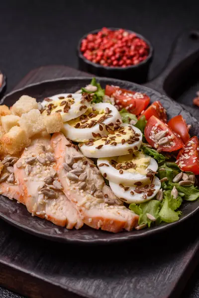 İçinde tavuk, parmesan peyniri, domates, kızarmış ekmek, marul yaprağı, keten tohumu, ayçiçeği ve susam tohumları olan bir kâse dolusu sezar salatası.