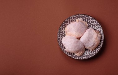 Tek renkli arka planda tuz ve baharatlı taze tavuk budu eti.