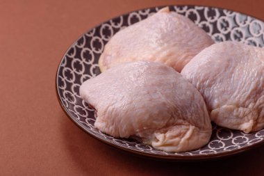 Tek renkli arka planda tuz ve baharatlı taze tavuk budu eti.