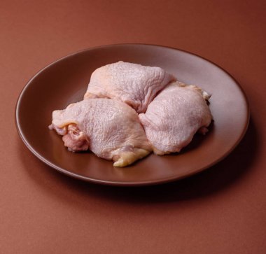 Tek renkli arka planda tuz ve baharatlı taze tavuk budu eti.