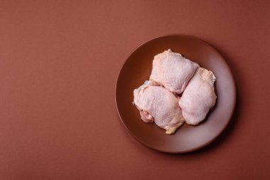 Tek renkli arka planda tuz ve baharatlı taze tavuk budu eti.