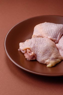 Tek renkli arka planda tuz ve baharatlı taze tavuk budu eti.