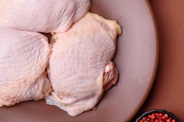 Tek renkli arka planda tuz ve baharatlı taze tavuk budu eti.