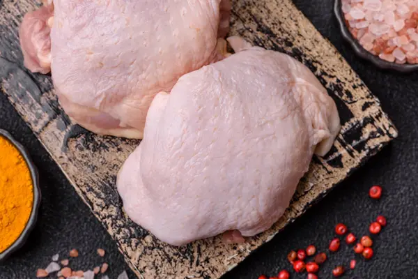 Tek renkli arka planda tuz ve baharatlı taze tavuk budu eti.