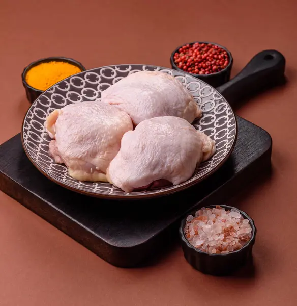 Tek renkli arka planda tuz ve baharatlı taze tavuk budu eti.