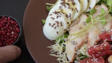 İçinde tavuk, parmesan peyniri, domates, kızarmış ekmek, marul yaprağı, keten tohumu, ayçiçeği ve susam tohumları olan bir kâse dolusu sezar salatası.