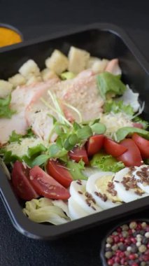 İçinde tavuk, parmesan peyniri, domates, kızarmış ekmek, marul yaprağı, keten tohumu, ayçiçeği ve susam tohumları olan bir kâse dolusu sezar salatası.