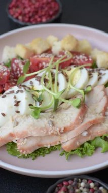 İçinde tavuk, parmesan peyniri, domates, kızarmış ekmek, marul yaprağı, keten tohumu, ayçiçeği ve susam tohumları olan bir kâse dolusu sezar salatası.