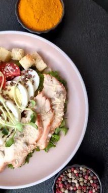 İçinde tavuk, parmesan peyniri, domates, kızarmış ekmek, marul yaprağı, keten tohumu, ayçiçeği ve susam tohumları olan bir kâse dolusu sezar salatası.