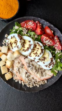 İçinde tavuk, parmesan peyniri, domates, kızarmış ekmek, marul yaprağı, keten tohumu, ayçiçeği ve susam tohumları olan bir kâse dolusu sezar salatası.