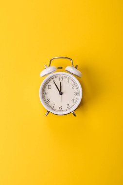 Ofis ve iş yerlerindeki son teslim tarihleri için kavramsal bir arkaplan olarak sarı yüzeyde klasik alarm saati