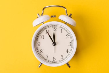 Ofis ve iş yerlerindeki son teslim tarihleri için kavramsal bir arkaplan olarak sarı yüzeyde klasik alarm saati