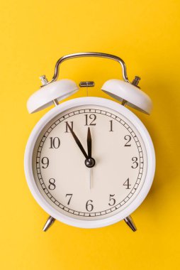 Ofis ve iş yerlerindeki son teslim tarihleri için kavramsal bir arkaplan olarak sarı yüzeyde klasik alarm saati